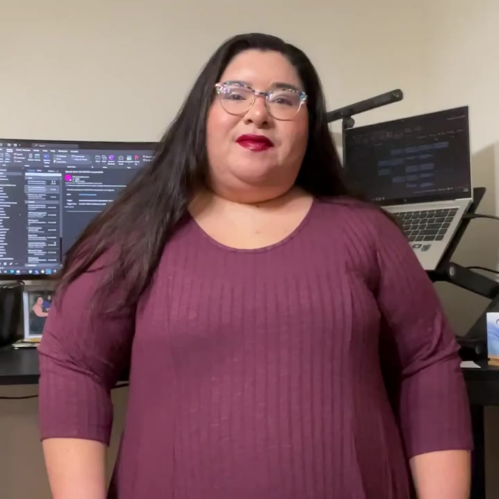 Laura, a participant in Merit America's Google Career Certificates program, stands in front of a computer